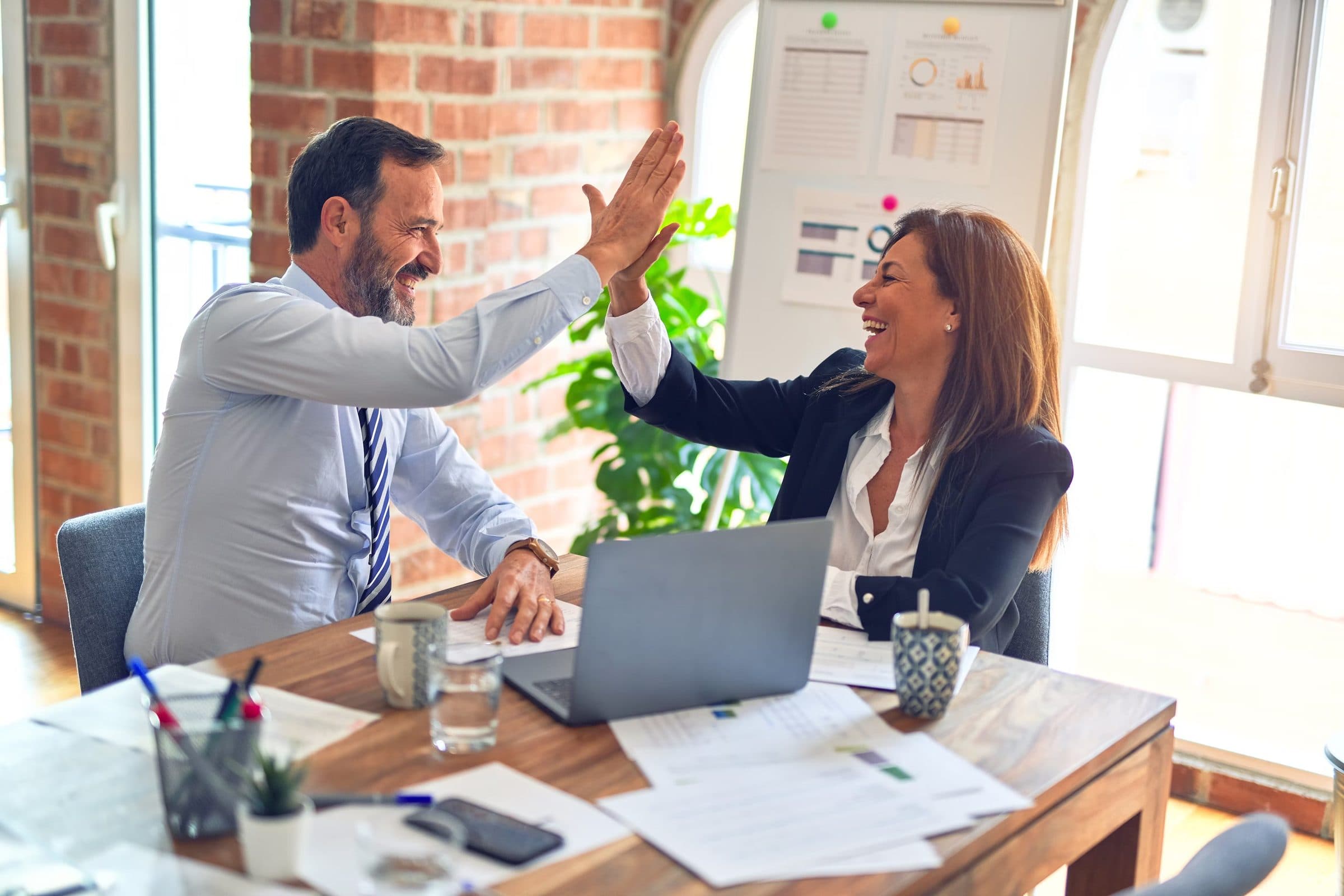 Two colleagues sharing a high five across a desk