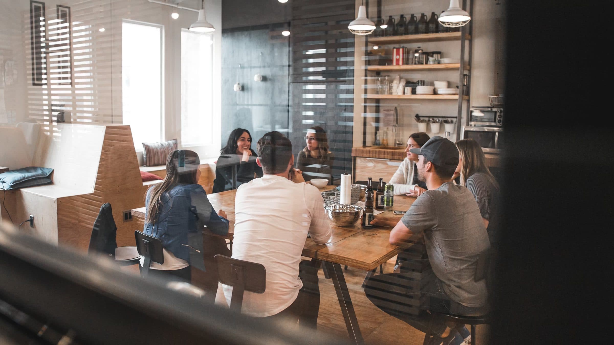 A team meeting at a wooden table, seen through glass